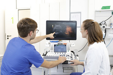 2 junge Ärzte besprechen den Befund einer Sonografie.